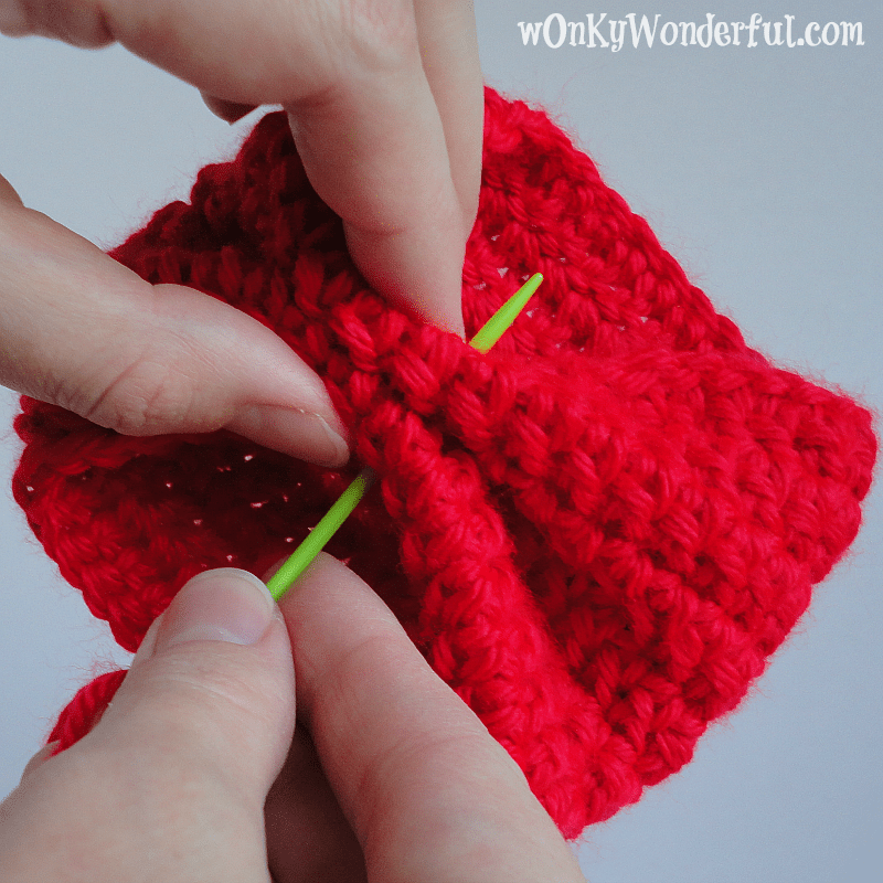 hand sewing crocheted cup cozy