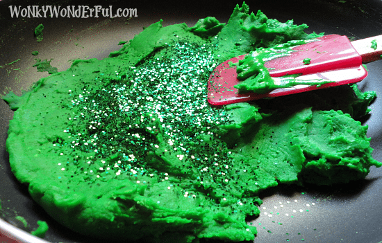 green play dough topped with glitter in pan with spatula
