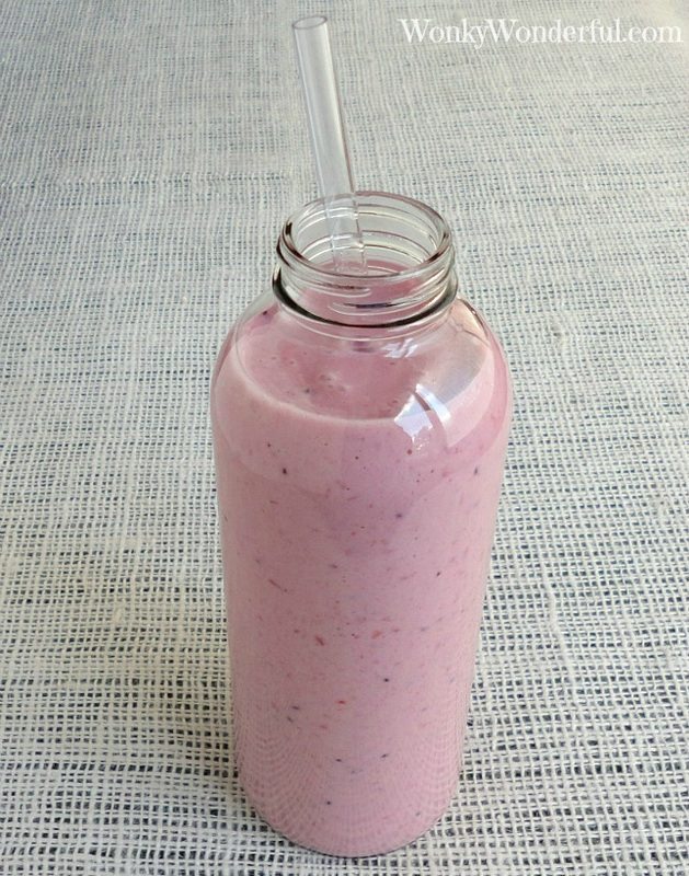 pink smoothie in clear glass bottle with straw