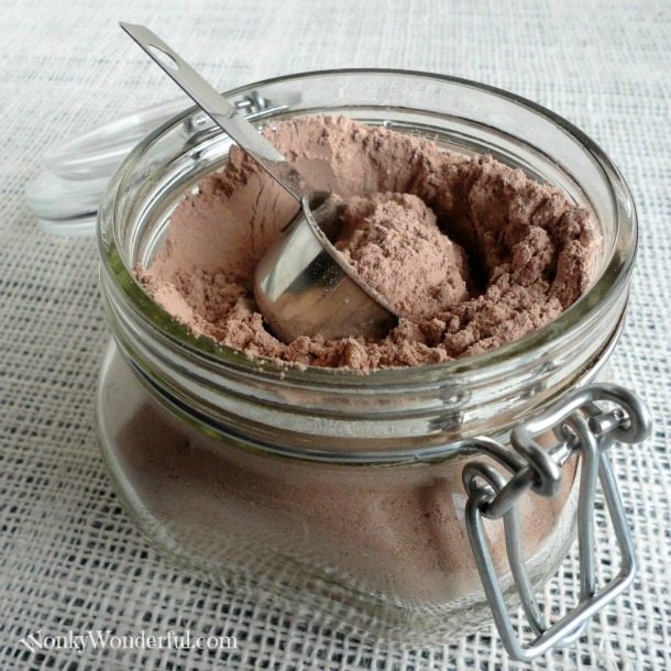 powdered cocoa mix in glass jar with metal scoop