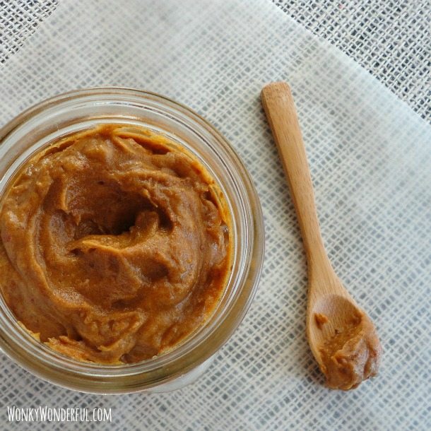 golden brown spread in glass jar next to small wood spoon