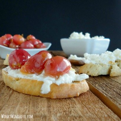 ricotta and roasted grape crostini on wooden board