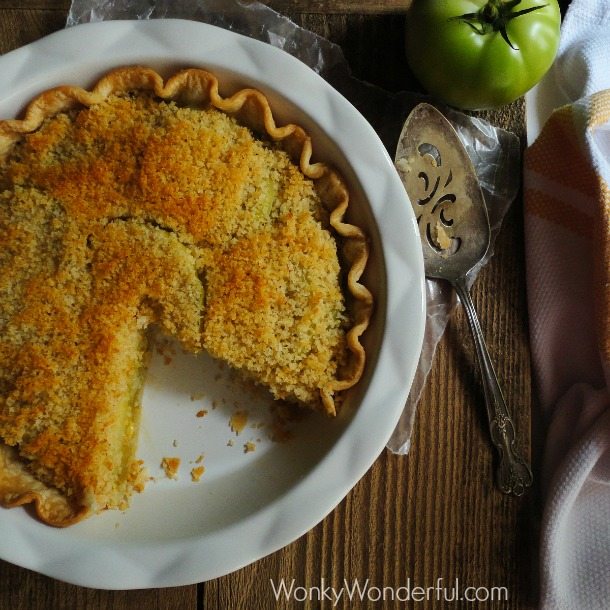 crusty topped pie in pie plate with green tomato and serving knife next to it