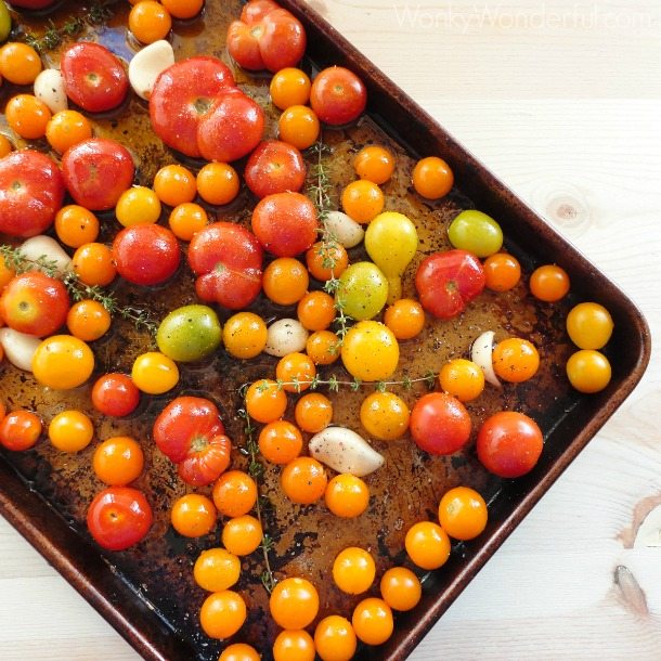 dark rimmed baking sheet with tomatoes, garlic and thyme