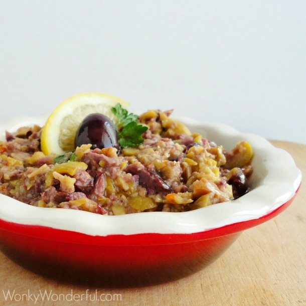 red dish filled with finely chopped olives topped with a lemon slice, olive and parsley