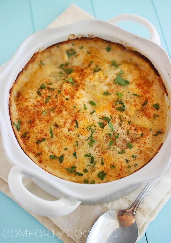 potatoes topped with melty cheese an d herbs in white dish