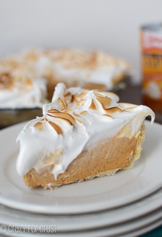 dark orange colored slice of pie topped with fluffy white topping served on white plates
