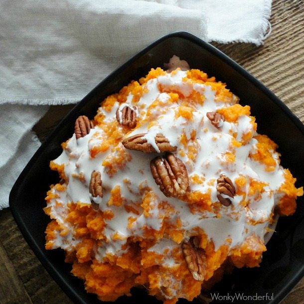 orange sweet potato mash topped with marshmallow and pecan in black bowl
