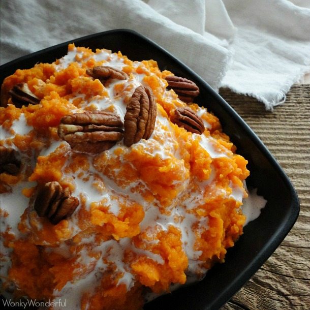 mashed sweet potatoes topped with marshmallow and pecans in black bowl