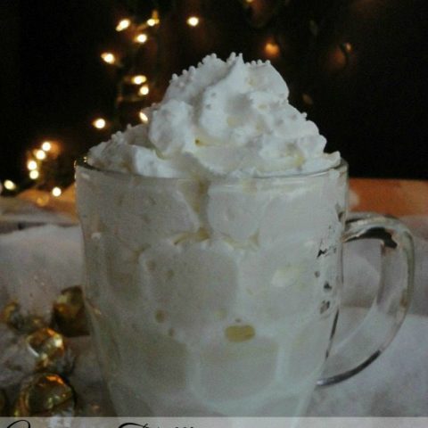 clear glass mug filled with white beverage and whipped cream - photo text: white truffle hot chocolate