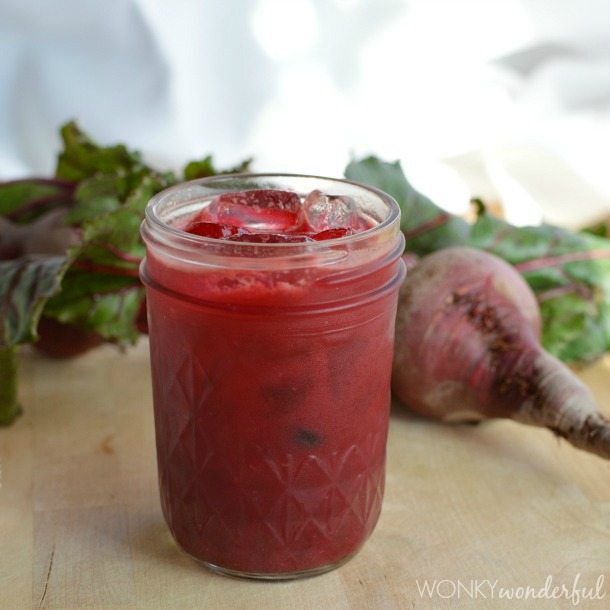 glass jar filled with red juice, fresh beets in the background
