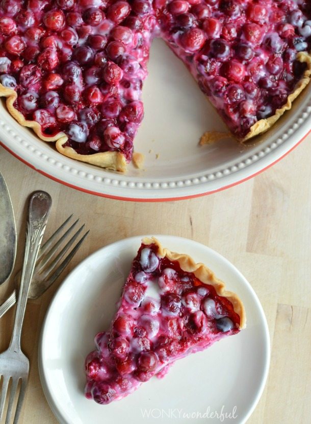 pie in pie plate next to plate with pie slice and forks