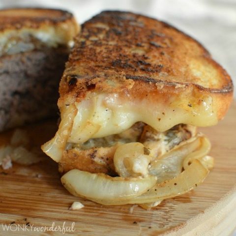 side view of cheesy patty melt cut in half, onions falling out