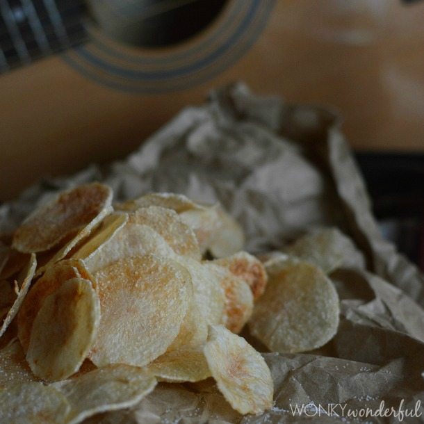 thinly sliced cooked potato chips on brown paper