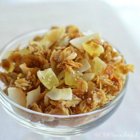oat granola with pineapple and coconut chunks in clear glass bowl