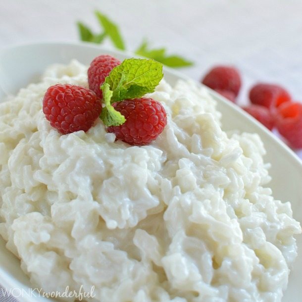 white rice pudding topped with raspberries and small mint leaves
