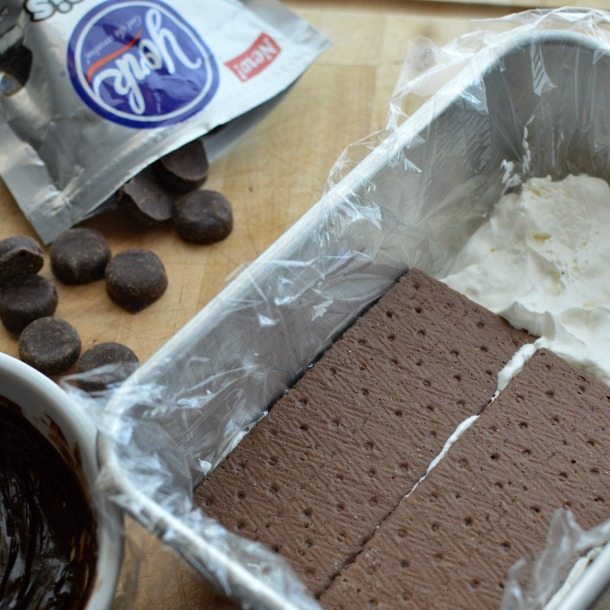 loaf pan filled with white cream topped with brown graham crackers with candy on the side