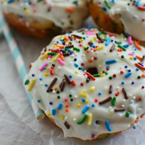 donuts topped with white glaze and colorful rainbow sprinkles