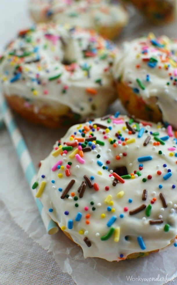 donuts topped with white glaze and colorful rainbow sprinkles