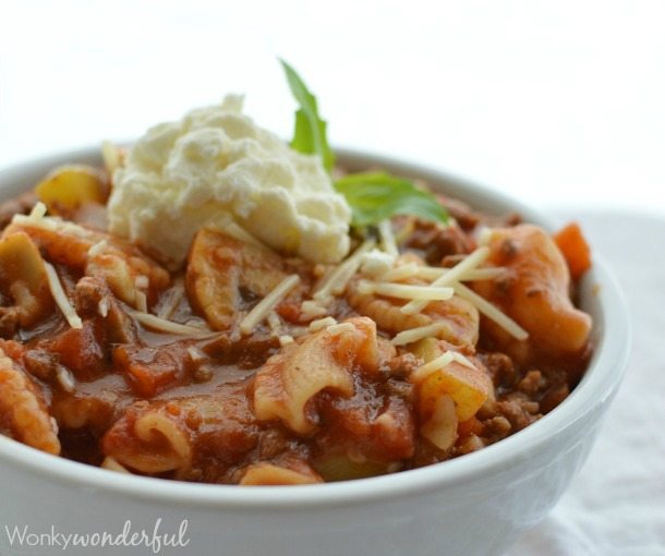 white bowl filled with saucy pasta topped with ricotta