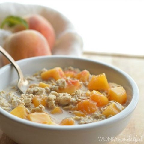 oatmeal and peaches in white bowl with spoon