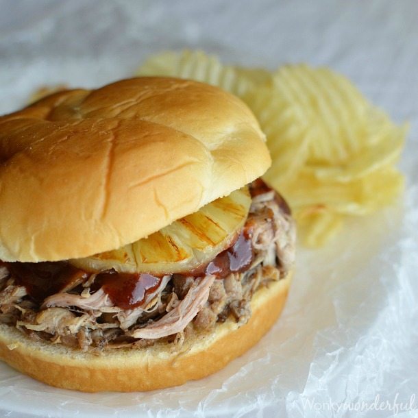 shredded pork and pineapple sandwich with chips in background