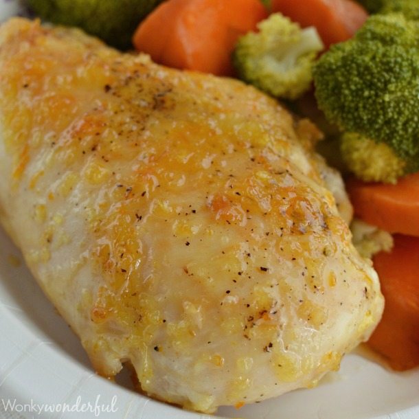 chicken breast coated with orange sauce next to veggies