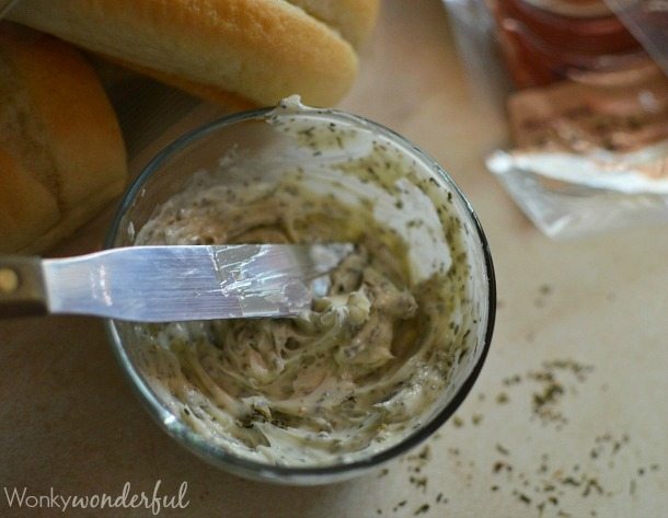 Hot Italian Sandwiches baked in the oven. Meaty Cheesy Sub Sandwiches, great for feeding a large crowd! #easydinner #gamedayfood #sandwiches herbed butter getting ready to spread onto rolls