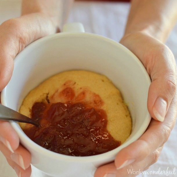 hands holding mug filled with cooked cake and jelly