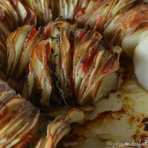 closeup of roasted sliced potatoes with bacon and thyme