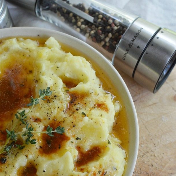 bowl of potatoes topped with melted butter and thyme