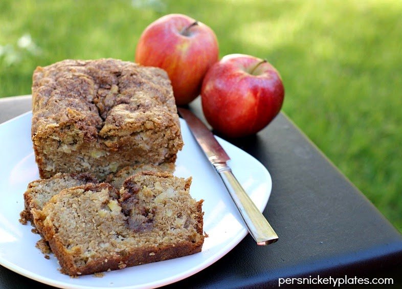 brown loaf with slices and gooey middle next to fresh apples