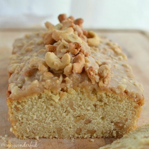 light tan quick bread topped with glaze and cashews