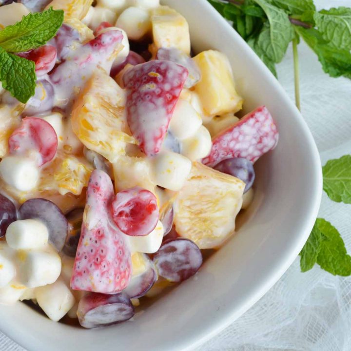 Enjoy Ambrosia Salad in a healthier way. This fruit salad is made with fresh fruit, dairy free yogurt alternative and mini marshmallows. A sweet dessert treat that is healthy!