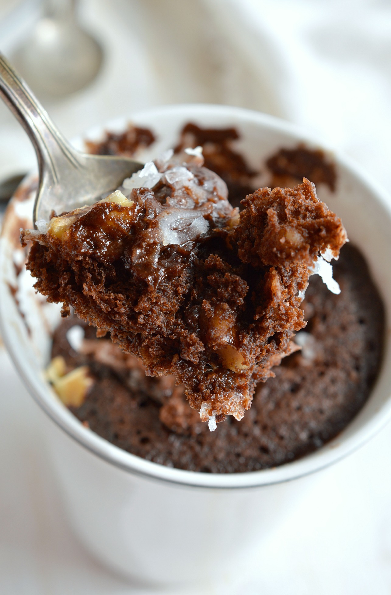 Craving chocolate and need a quick dessert fix? This Egg-Free, Dairy-Free German Chocolate Mug Cake Recipe is the solution! No eggs. No dairy. And this vegan chocolate cake is made in 5 minutes! #mugcakerecipes #cakerecipes #veganrecipes spoon with chocolate cake and coconut