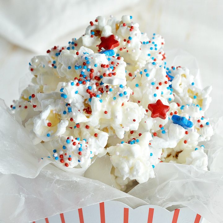 Make an easy and festive treat to enjoy while watching the fireworks. 4th of July Dessert Popcorn is popped microwave popcorn drizzled with white chocolate and topped with Red, White and Blue sprinkles! This patriotic dessert recipe is perfect for feeding a crowd!
