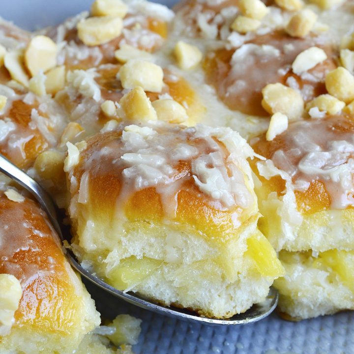 Pineapple Coconut Hawaiian Sweet Rolls in 20 minutes! Yes, it is possible. Sweet Hawaiian rolls stuffed with pineapple and coconut then drizzled with a pineapple glaze. Top with macadamia nuts for the ultimate tropical inspired dessert recipe.