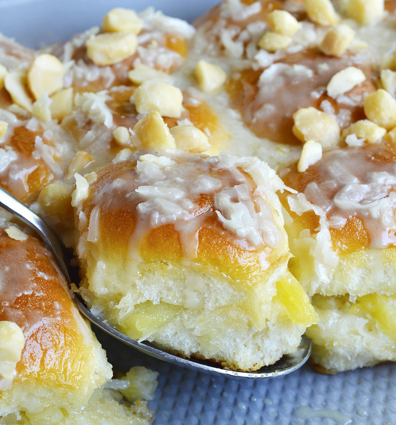 Pineapple Coconut Hawaiian Sweet Rolls in 20 minutes! Yes, it is possible. Sweet Hawaiian rolls stuffed with pineapple and coconut then drizzled with a pineapple glaze. Top with macadamia nuts for the ultimate tropical inspired dessert recipe.