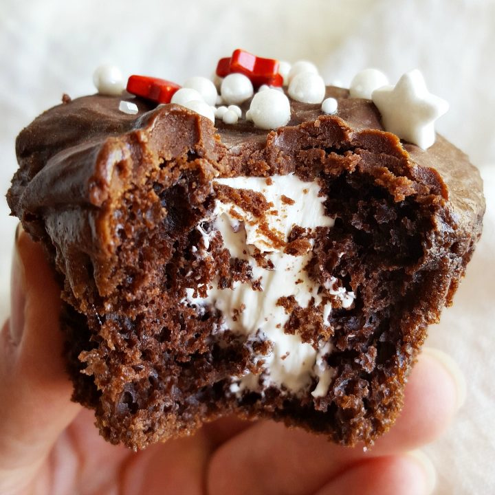 These Cream Filled Cupcakes are super easy to make and are sure to be a hit! Cake mix chocolate cupcakes are filled with luscious vanilla cream then topped with chocolate glaze frosting and sprinkles. This semi-homemade dessert recipe is just one of many treats from The Domestic Rebel's new cookbook, Out of the Box Treats.