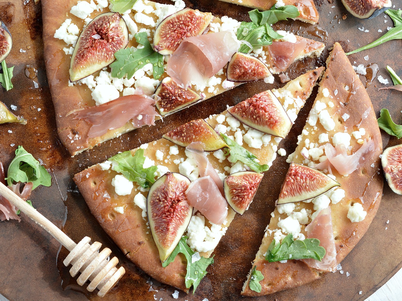 If you need a quick and easy dinner idea I am here for you! This Fig and Prosciutto Flatbread Pizza Recipe is great no-fuss meal. Fresh figs, crumbled goat cheese, prosciutto, peppery greens, honey and flaked salt make this flatbread pizza ultra delicious . . . and perfect with a glass of wine!