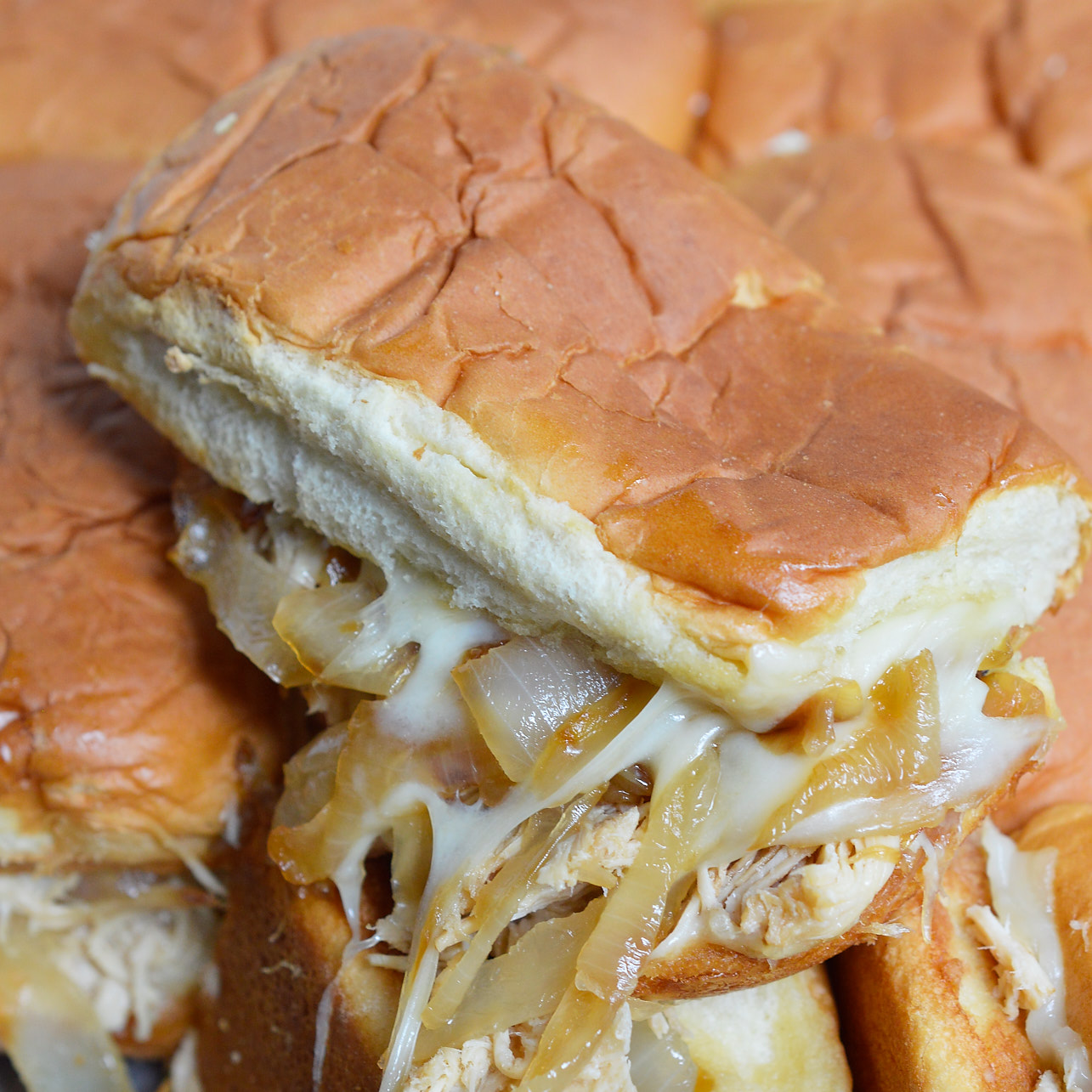 These Cheesy French Onion Chicken Sandwiches are the ultimate party or game day food! Soft rolls loaded up with slow cooker chicken, caramelized onions and loads of melt cheese. This is the perfect recipe to feed your hungry crowd!