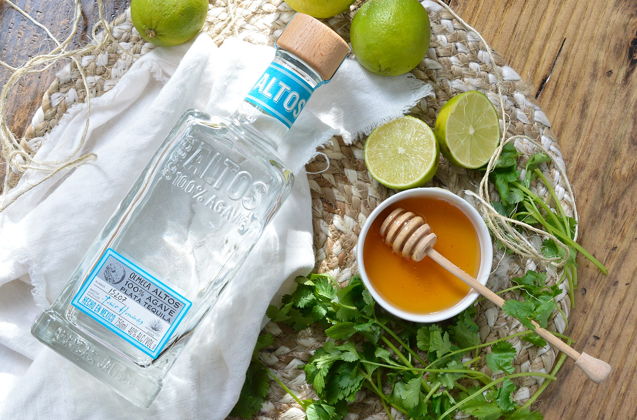 ingredient photo with tequila bottle, honey, limes and cilantro