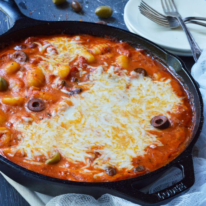 Do you want an easy dinner with unique flavor? This Puttanesca Baked Gnocchi Recipe is a fun twist on a traditional pasta meal! Gnocchi are slathered in this briny red sauce filled with olives then topped with mozzarella and baked to perfection.