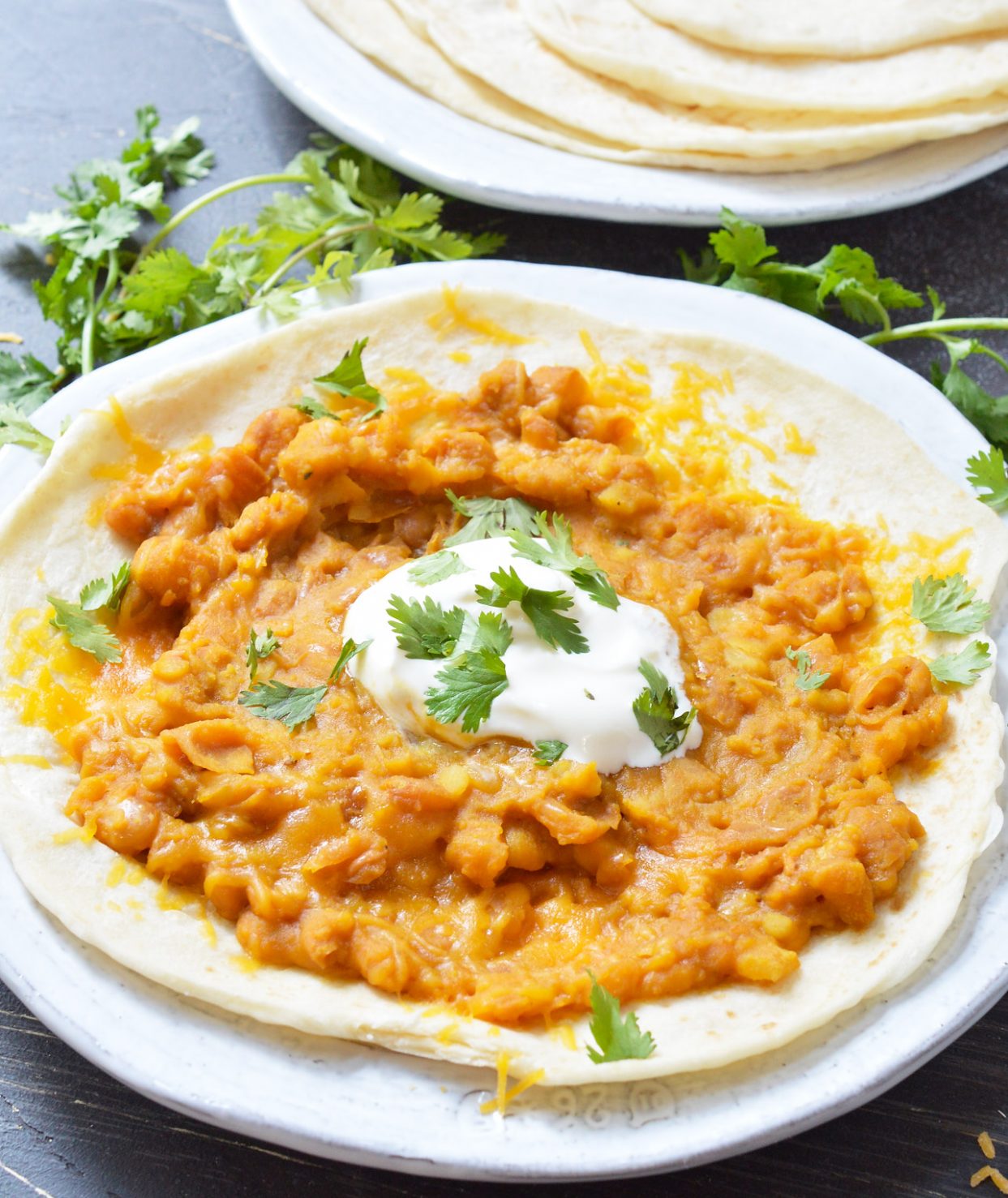 tortilla topped with refried beans on white plate