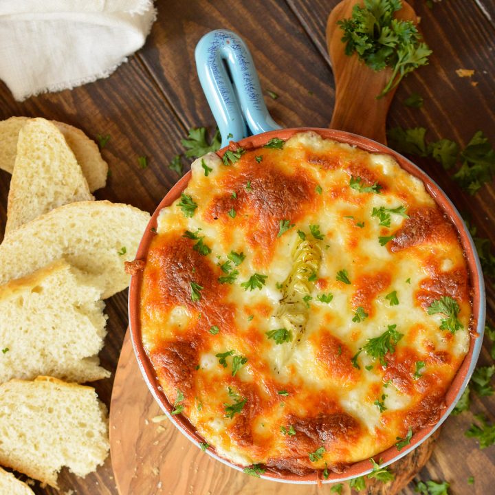 above view of baked dip with browned cheese top, bread slices on the side