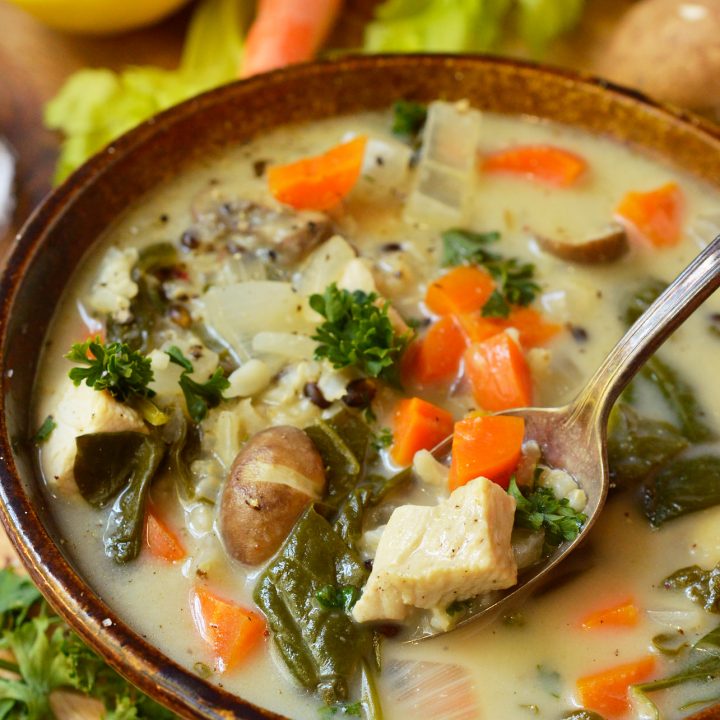 spoon scooping soup out of brown bowl