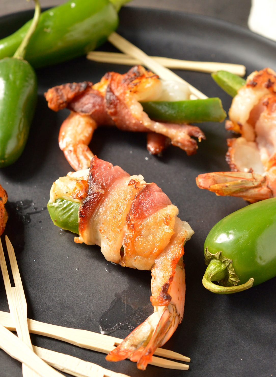 close up of bacon wrapped shrimp next to jalapeños