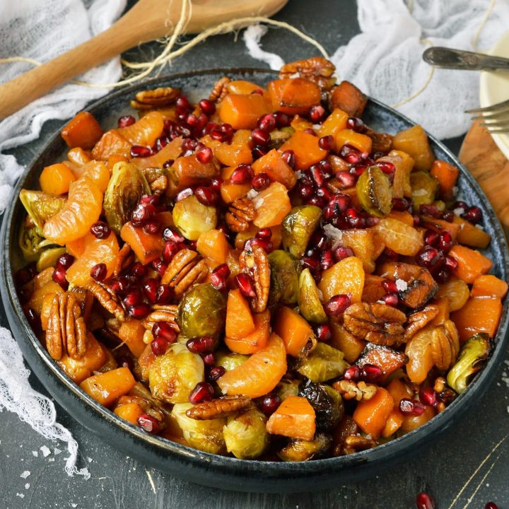 blue serving bowl filled with butternut squash chunks, orange segments, pecans and pomegranate seeds