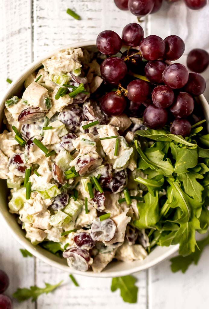 chicken salad with red grapes and green leafies in white bowl