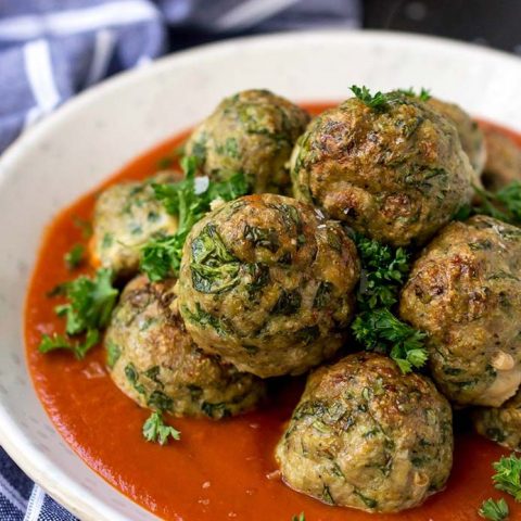 baked turkey meatballs with spinach in white bowl with red sauce